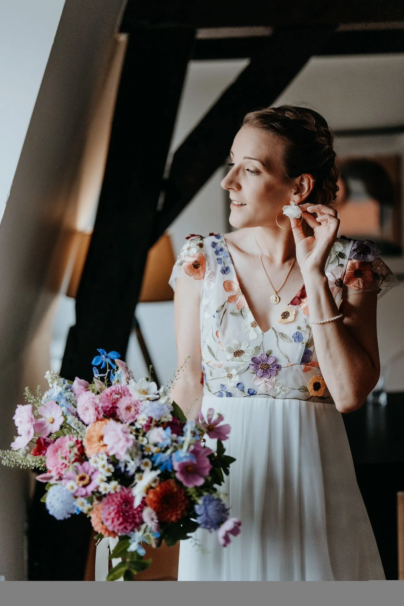Mariée en robe fleurie ajustant ses boucles d'oreilles