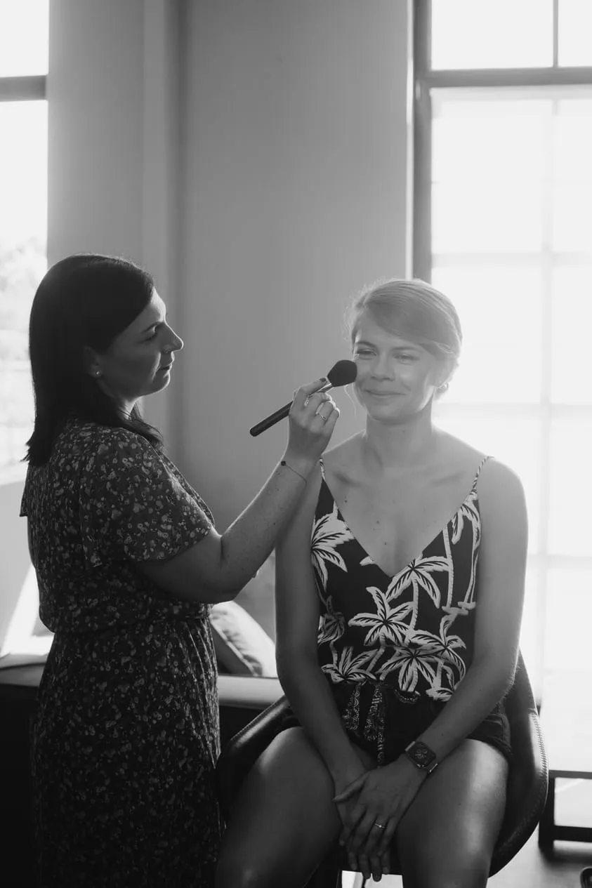 Kelly Clément appliquant le blush d'une cliente en lumière naturelle