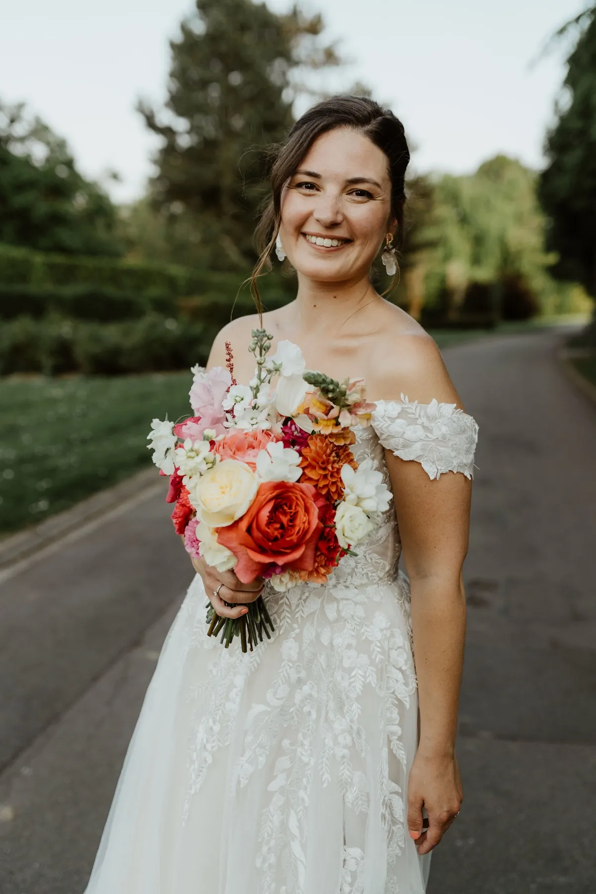 Mariée souriante en robe de dentelle, tenant un bouquet coloré