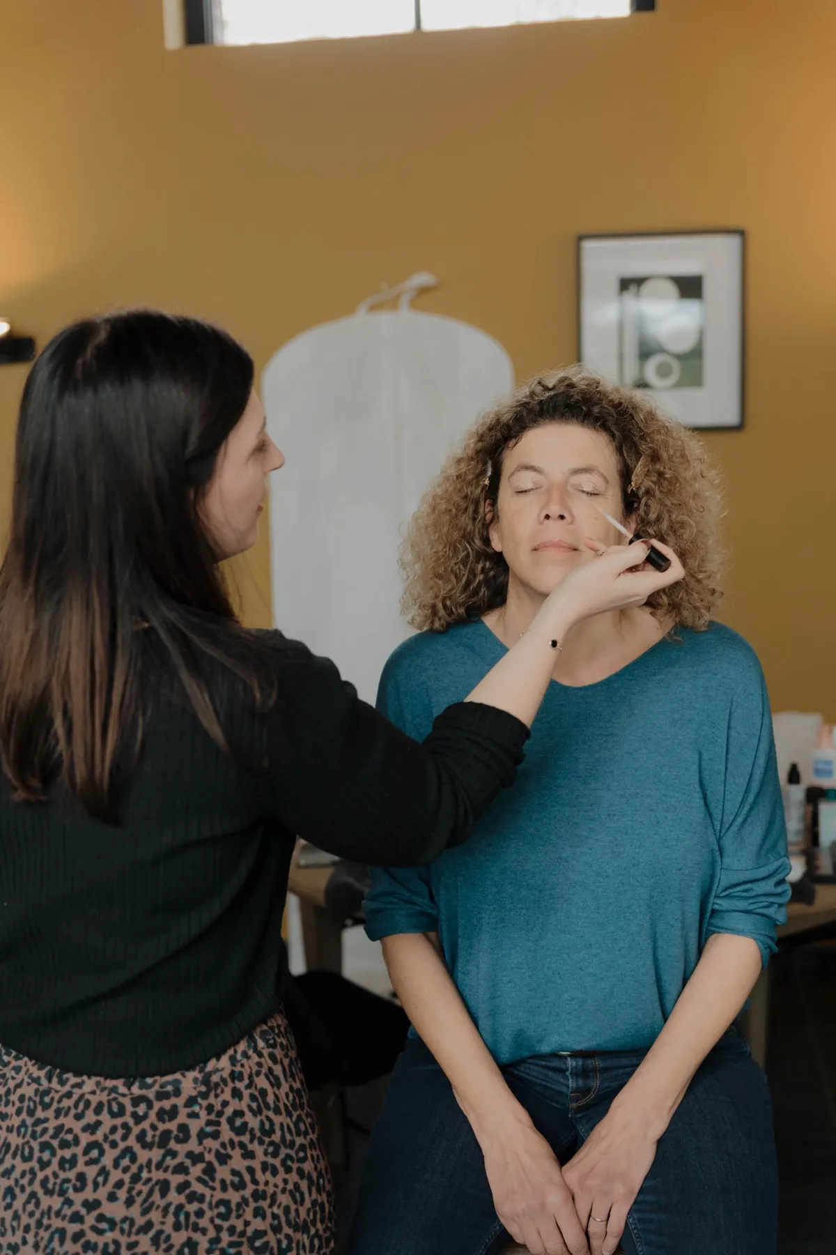 Kelly Clément appliquant un fard à paupières sur une cliente aux cheveux bouclés